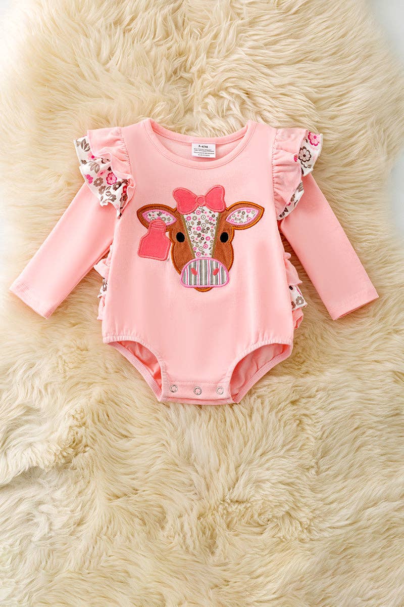 Pink cow applique baby bodysuit with floral ruffle on sleeves and ruffle butt.