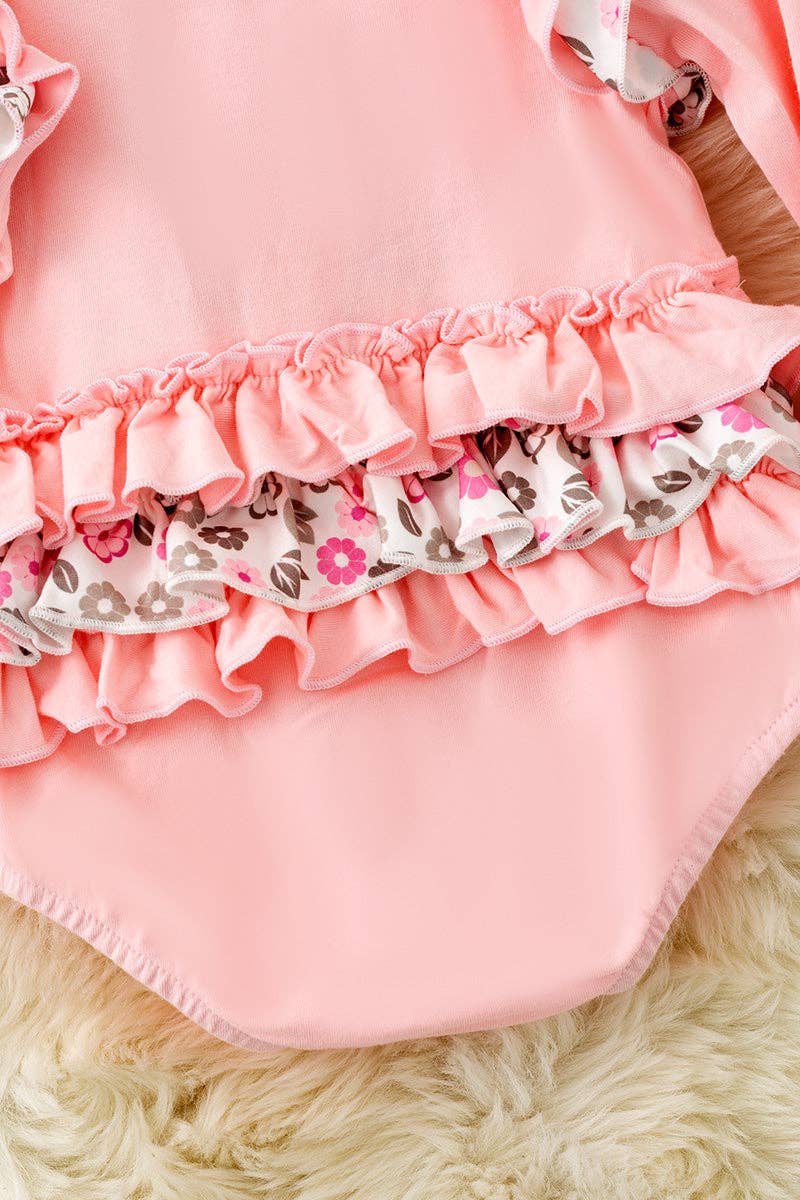 Pink cow applique baby bodysuit with floral ruffle on sleeves and ruffle butt.